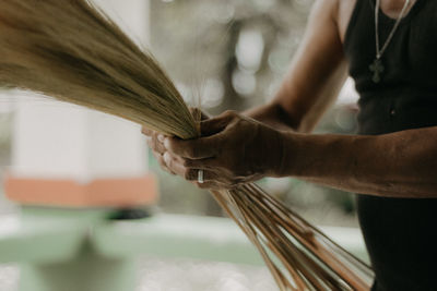 Close-up of person working on handcrafted walis tambo or brooms