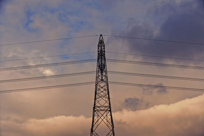 Low angle view of electricity pylon against sky during sunset