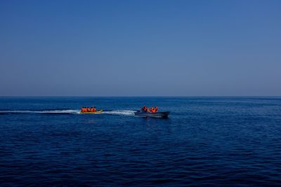 People in boats on sea against sky