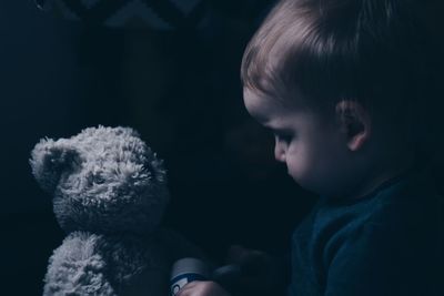 Close-up of toddler playing with teddy bear in darkroom
