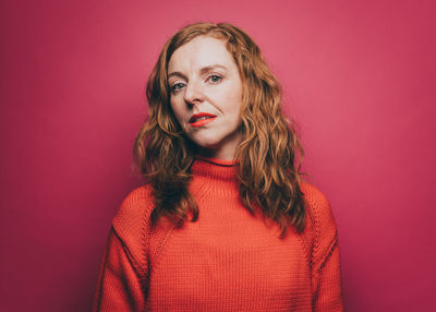 Portrait of beautiful young woman against red background