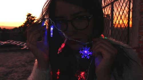 Close-up of woman in illuminated park against sky at night