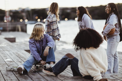 Happy female friends spending leisure time on pier during sunset