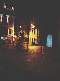 Illuminated people walking on footpath by building at night