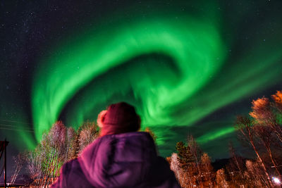 Rear view of man standing against illuminated sky at night