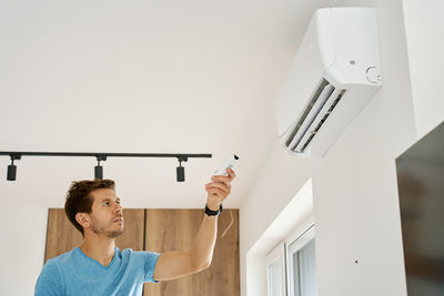 Low angle view of young woman standing against wall