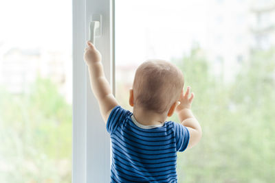 Rear view of boy standing by window