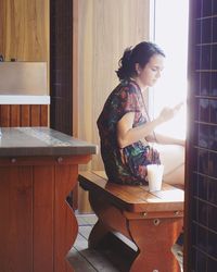 Young woman standing on table at home