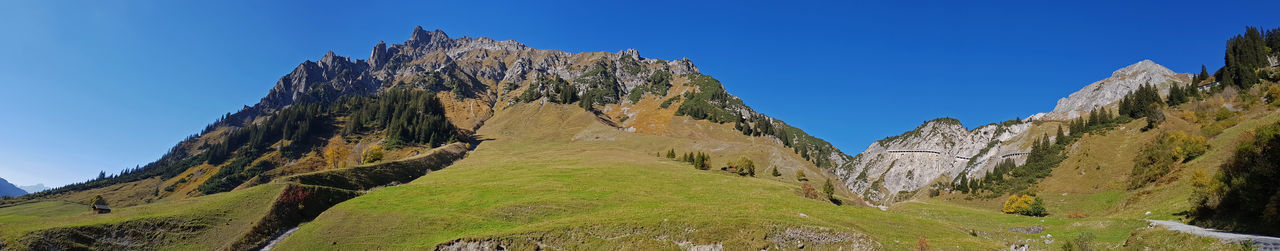 Panoramic view of rocky mountains against clear blue sky