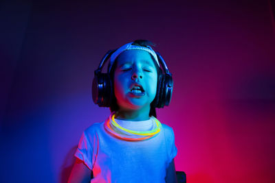 Cyberpunk boy child in a white t shirt and large headphones listening to music on the background 