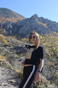 Portrait of woman wearing sunglasses while standing against mountain range and sky