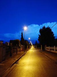 Empty road along trees at night