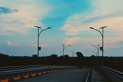 Street light on highway against sky during sunset