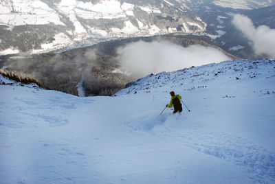 Man skiing on snowcapped mountain against sky