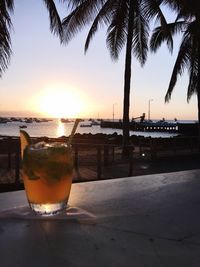 Close-up of beer on table against sea during sunset