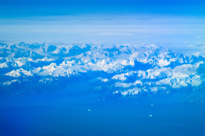 Aerial view of snowcapped landscape against blue sky