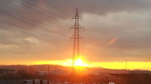 Low angle view of silhouette electricity pylon against sky during sunset