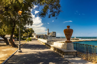 Footpath by sea against sky in city