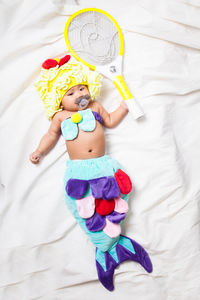 High angle view of baby girl in mermaid costume lying on bed at home