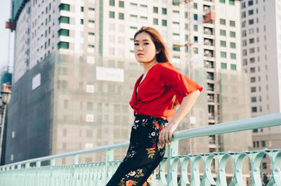 Woman leaning on railing against buildings in city