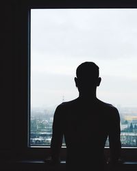 Silhouette man standing at window