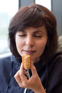 A beautiful adult woman in a cafe is happy to try a mini eclair cake.