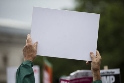 Close-up of hand holding placard against blurred background