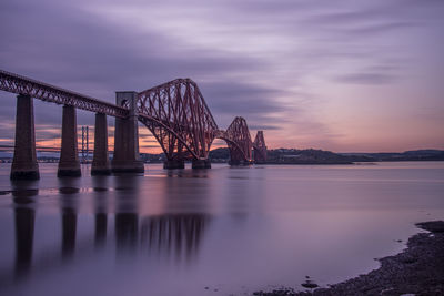 View of suspension bridge over river at sunset
