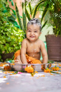 Cute toddler baby boy bathing with shampoo in decorated bathtub at outdoor from unique perspective