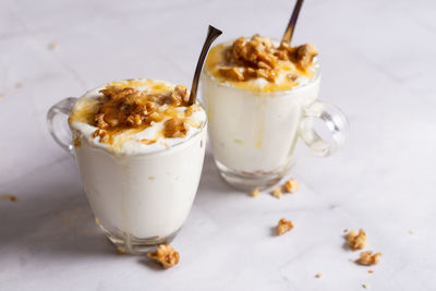 Cups of yogurt with honey and nuts on white background