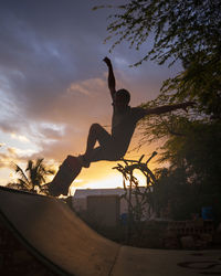 Low angle view of silhouette man jumping against sky