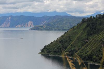 Scenic view of river by mountains against sky