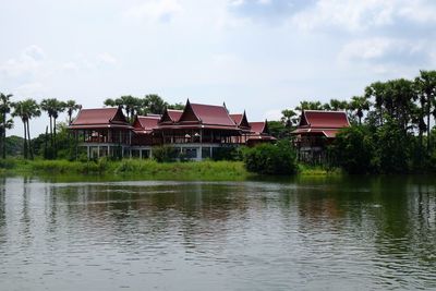 Houses by lake and buildings against sky