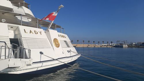 Sailboats moored in sea against clear blue sky