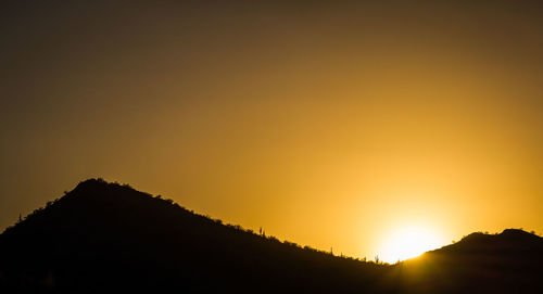 Scenic view of silhouette mountains against orange sky