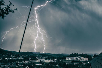 Panoramic view of lightning over buildings against sky