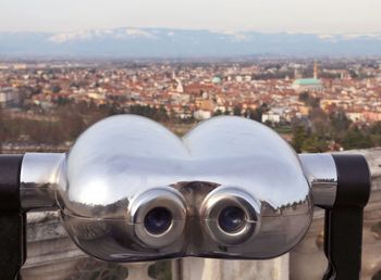 Close-up of coin-operated binoculars against buildings in city