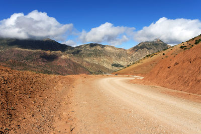 Scenic view of road by mountains against sky