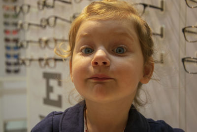 Close-up portrait of cute girl against eyeglasses in store