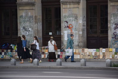 Full length of people by books arranged for sale on sidewalk