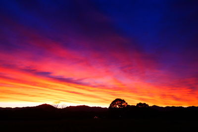 Silhouette landscape against dramatic sky during sunset