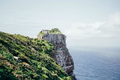 Scenic view of cliff by sea against sky