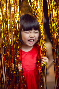 Portrait of a beautiful korean baby girl in a red dress at christmas with a gold decoration