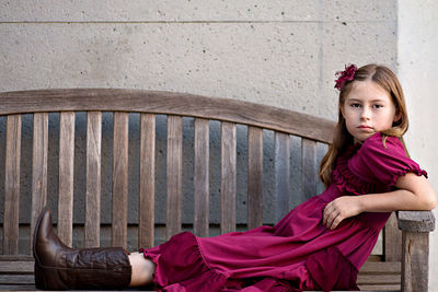 Portrait of young woman sitting on wall