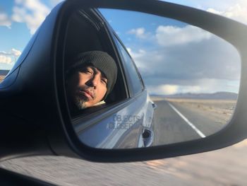 Portrait of man reflecting on side-view mirror