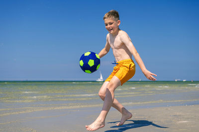 Full length of boy on beach against clear sky