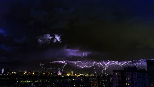 Lightning over illuminated buildings in city at night