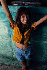 Portrait of young woman standing against wall