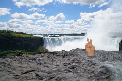 Scenic view of waterfall against cloudy sky