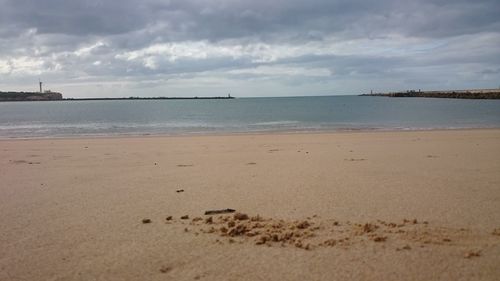 Scenic view of beach against cloudy sky